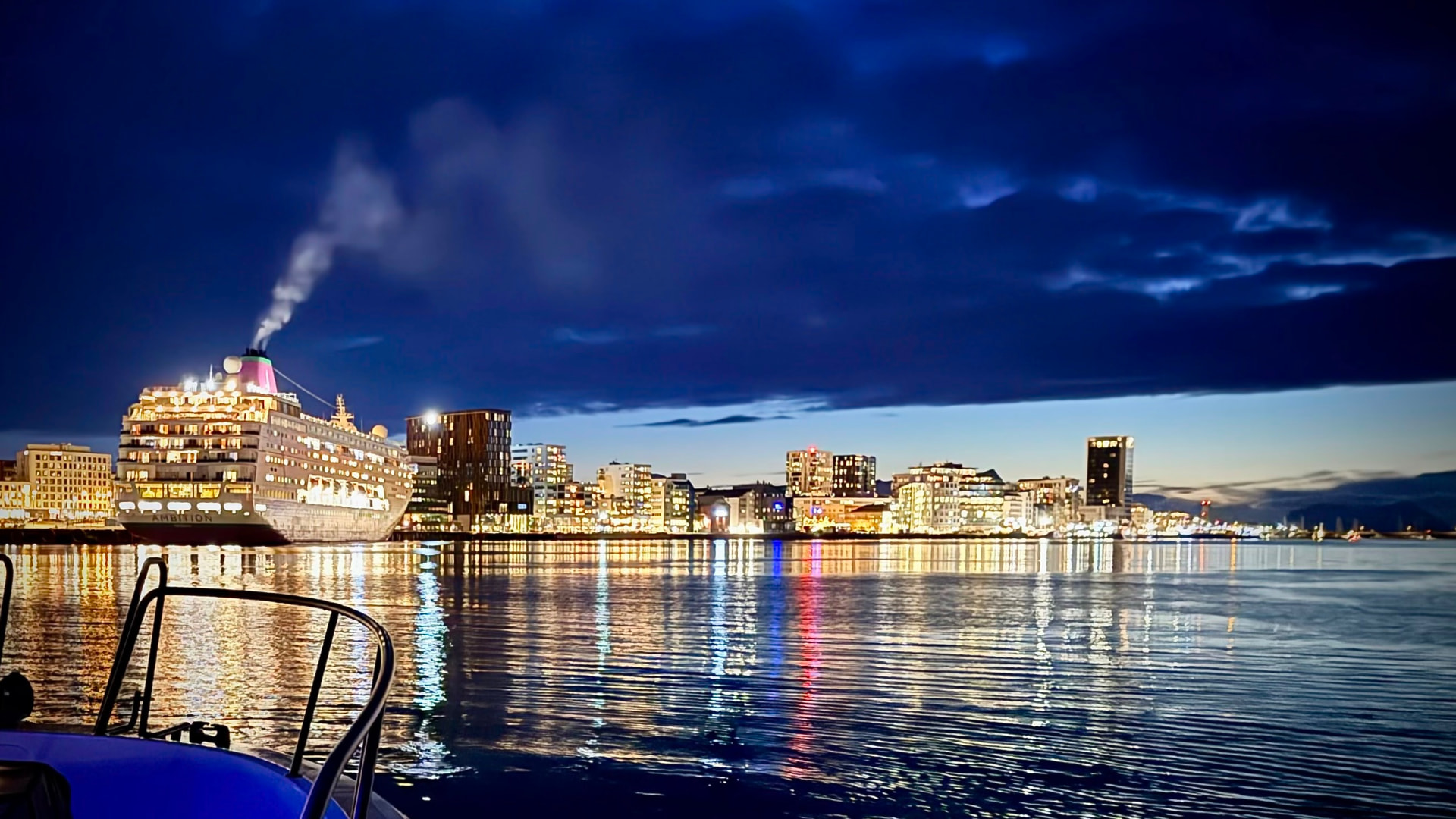 Bodø havn i skumringen med cruisebåt ved kaia og opplyste bygninger langs sjøkanten